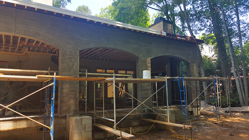 Covered porch under construction, with stucco arches, exposed rafters and scaffolding in place
