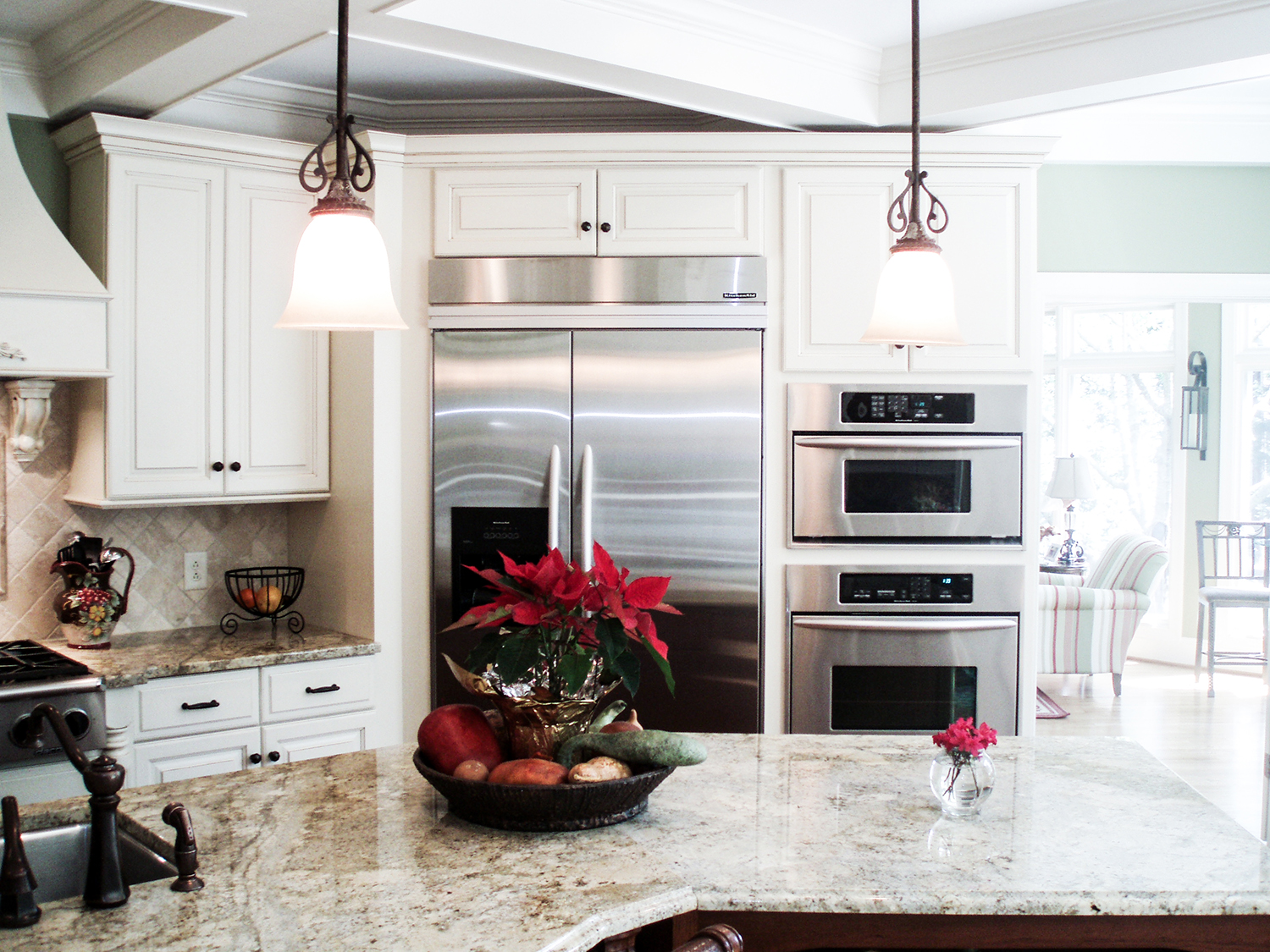 Remodeled kitchen with cream cabinets, a granite island and stainless steel appliances