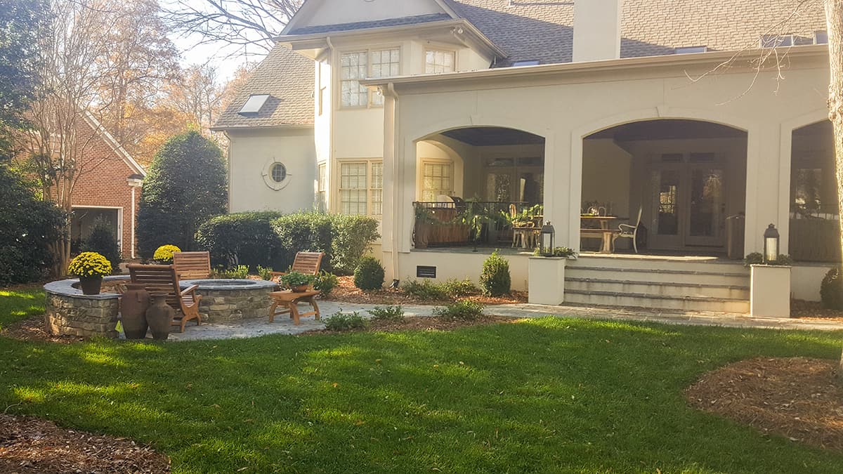 Covered outdoor living space with a stone fireplace at Providence Country Club, Charlotte